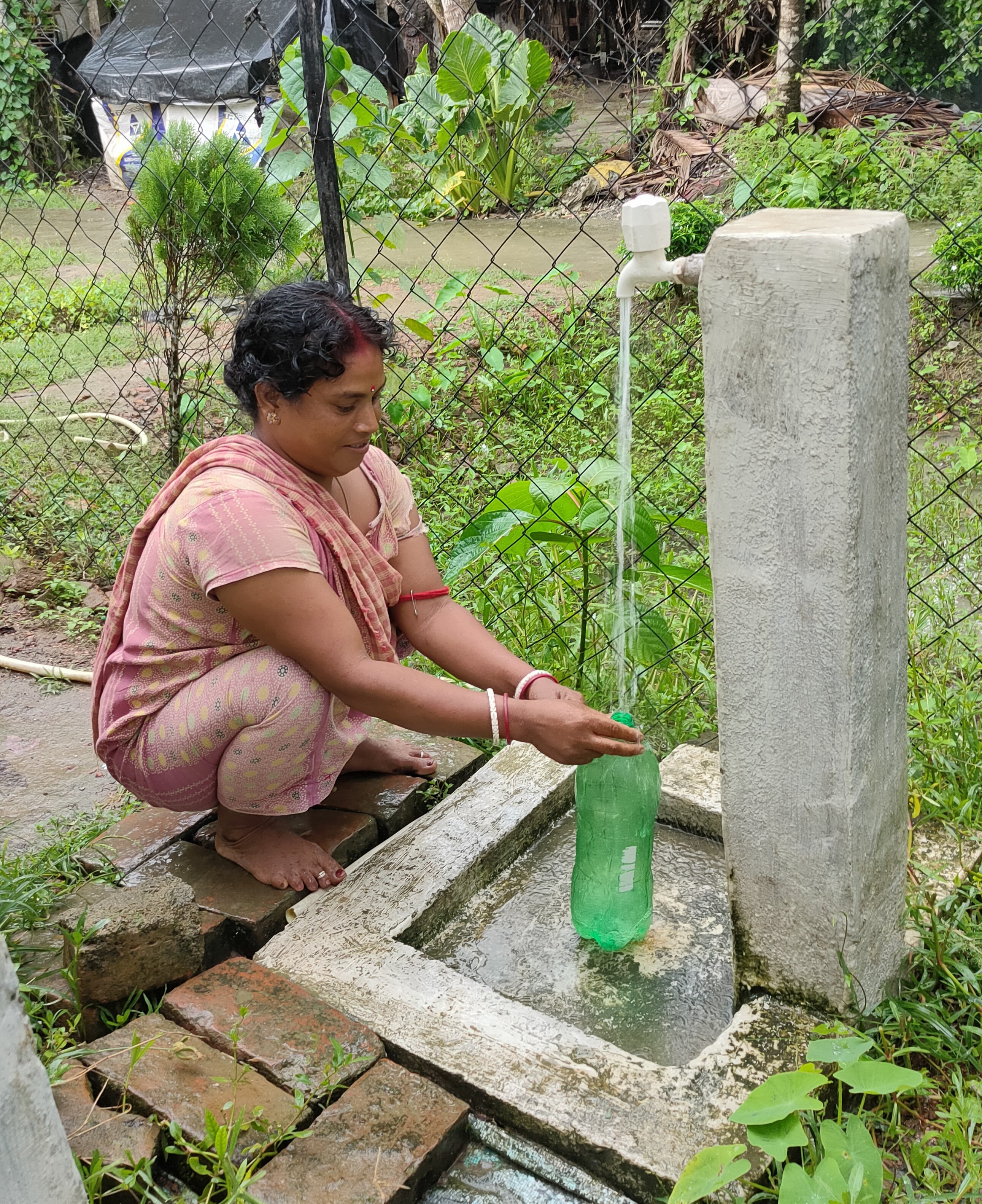 Frau holt Wasser an der Trinkwasseranlage Chatra